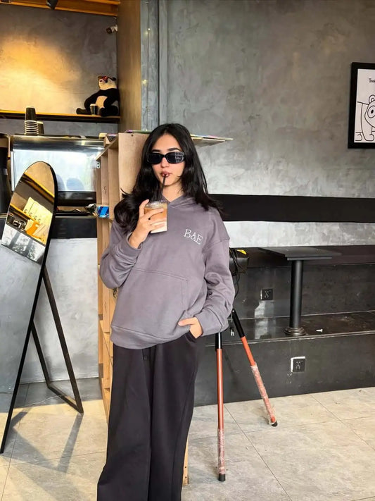 Girl wearing a gray hoodie with 'BAE' logo