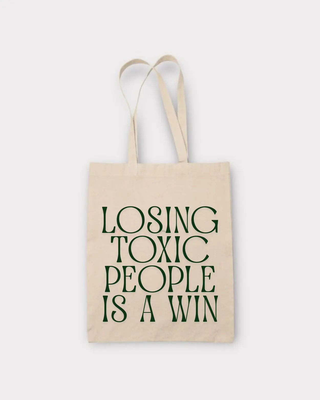 Beige tote bag with green text 'LOSING TOXIC PEOPLE IS A WIN'
